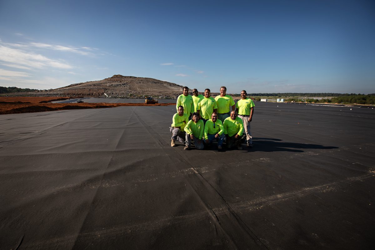 Group of Plastic Fusion Fabricators team members wearing green company shirts, standing together in a professional setting on the about page